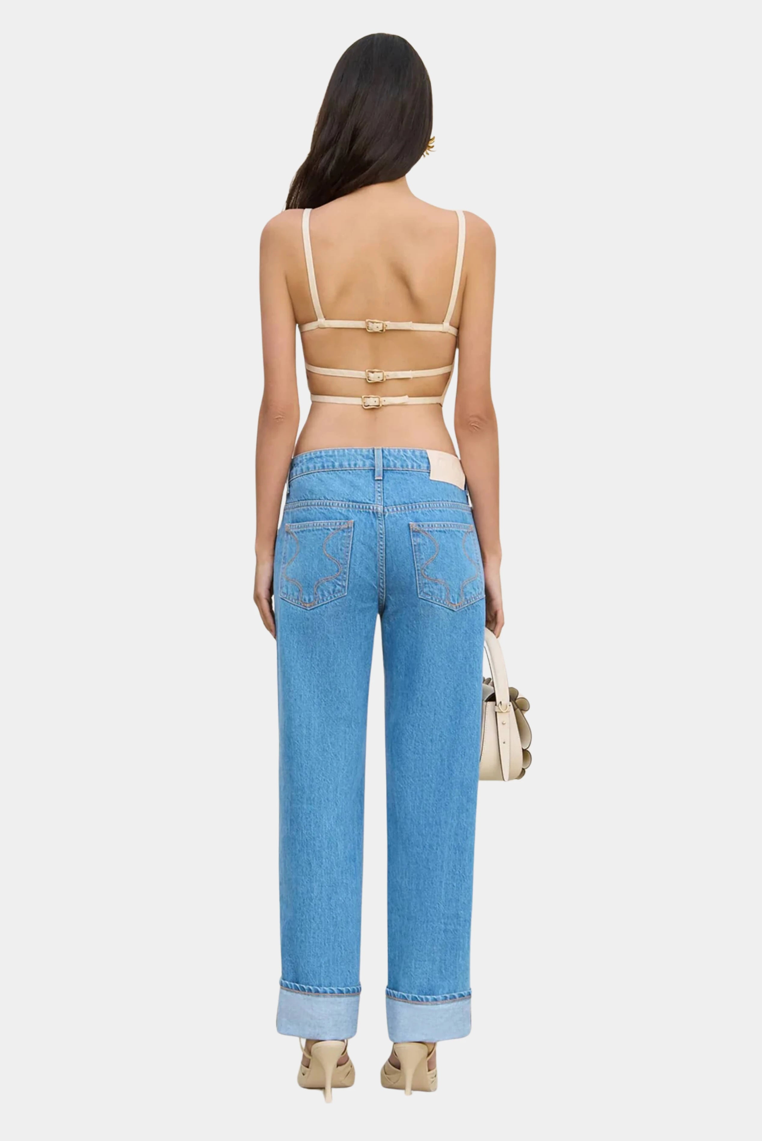 Top bege Cult Gaia com costas vazadas combinado com jeans de cintura baixa