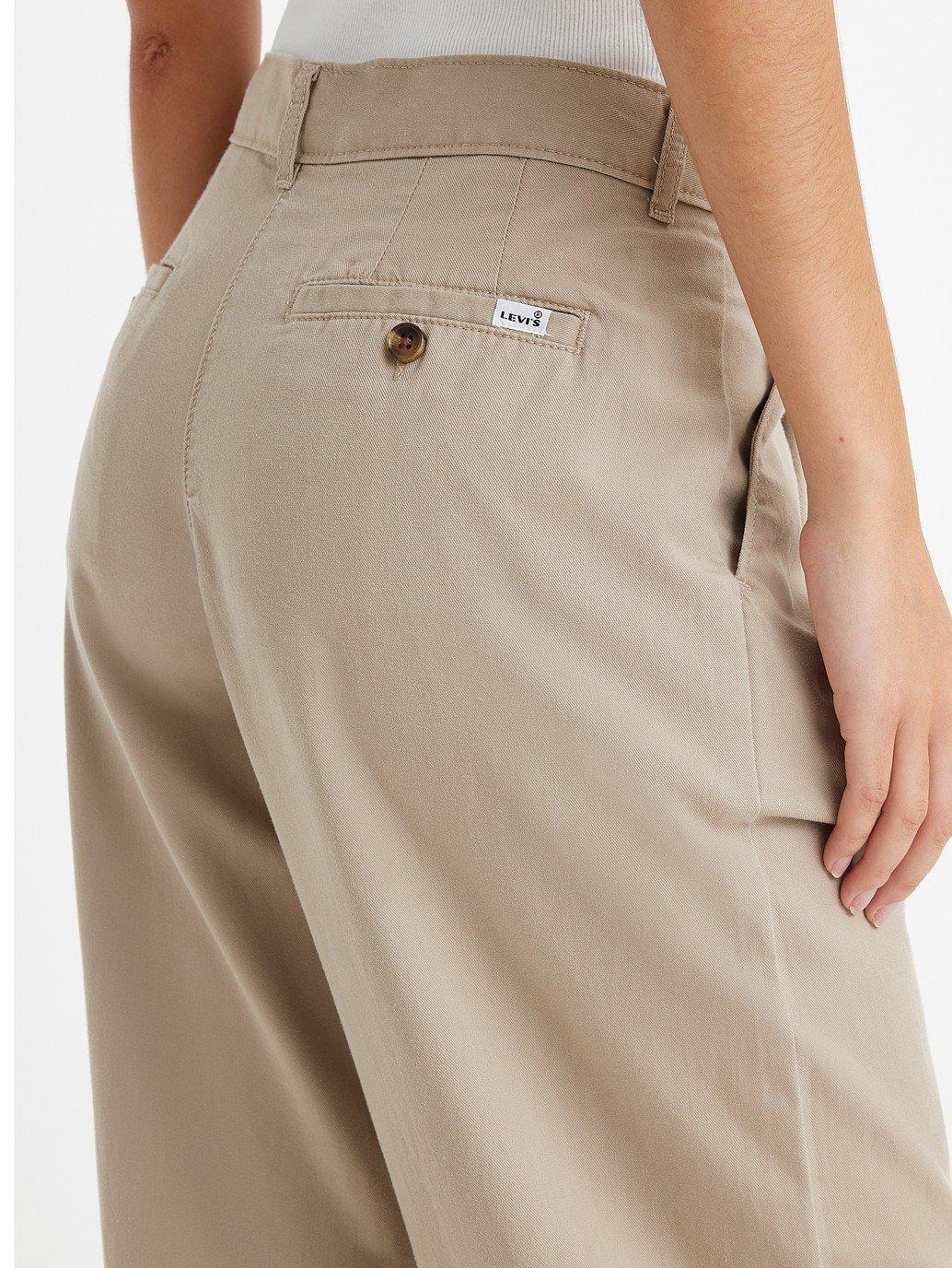 Detalhe do bolso traseiro da calça plissada bege com botão e etiqueta Levi's
