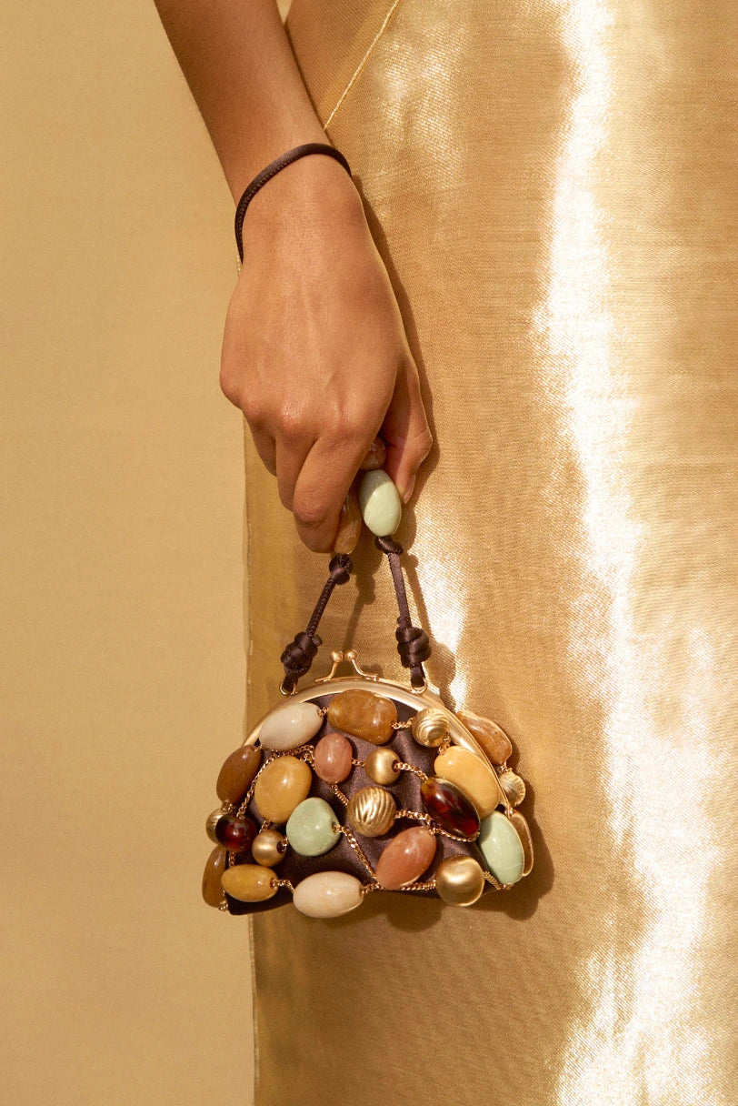 Modelo segurando a Bolsa Mercier Cult Gaia pela alça de pulso em look dourado