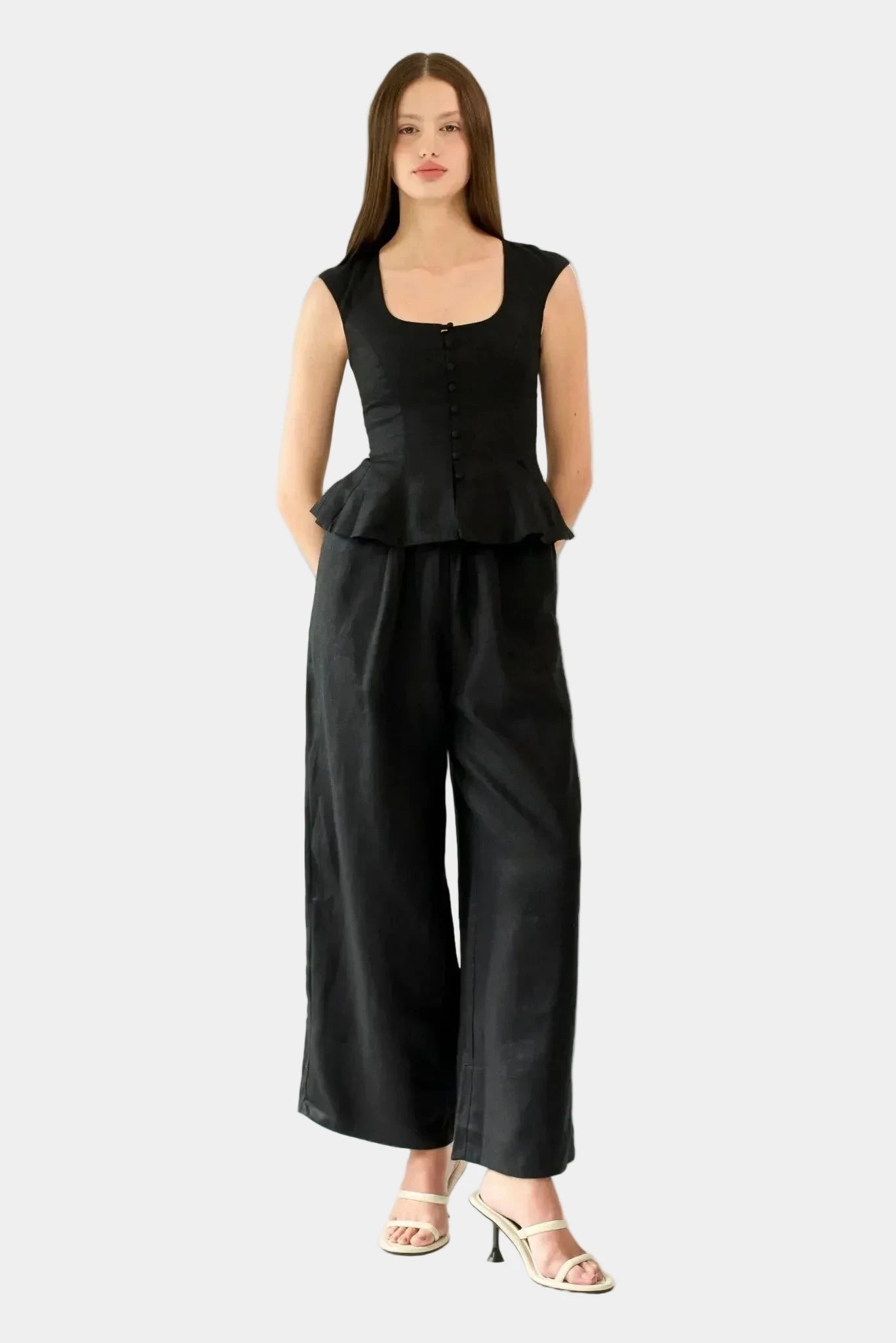 Modelo usando top preto em linho com botões frontais e barra peplum combinado com calça ampla
