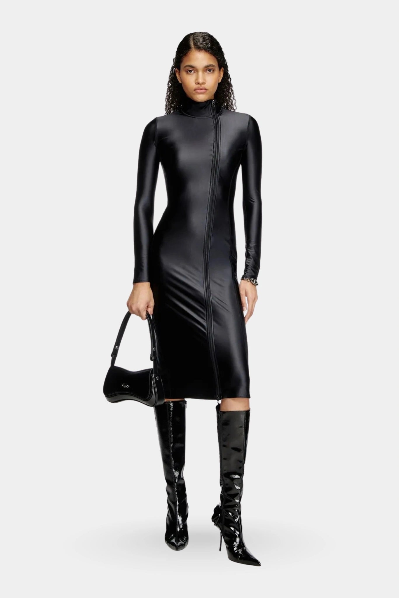 Modelo usando vestido preto Diesel ajustado com botas de cano alto